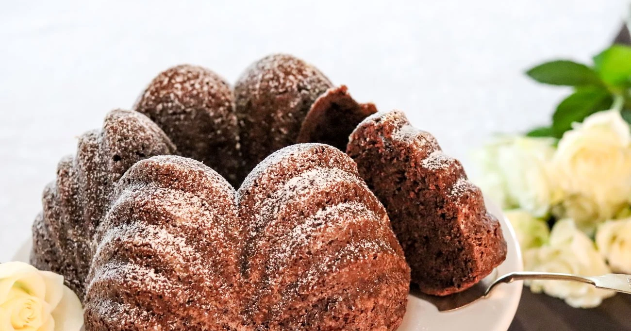 Suklainen piimäkakku valkoisten ruusujen vierellä.