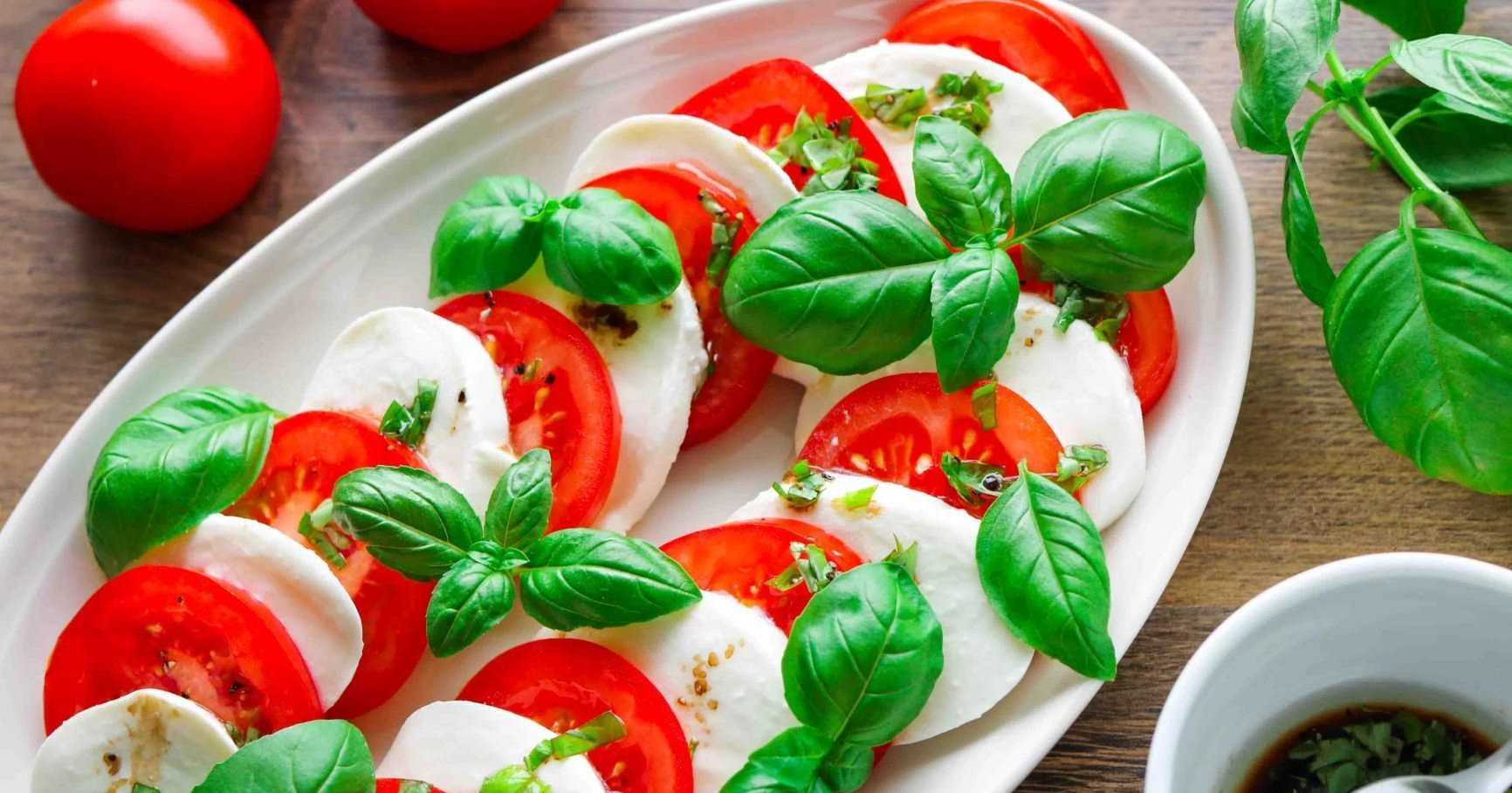 Tomaatti-mozzarellasalaatti basilikan lehdillä koristeltuna.