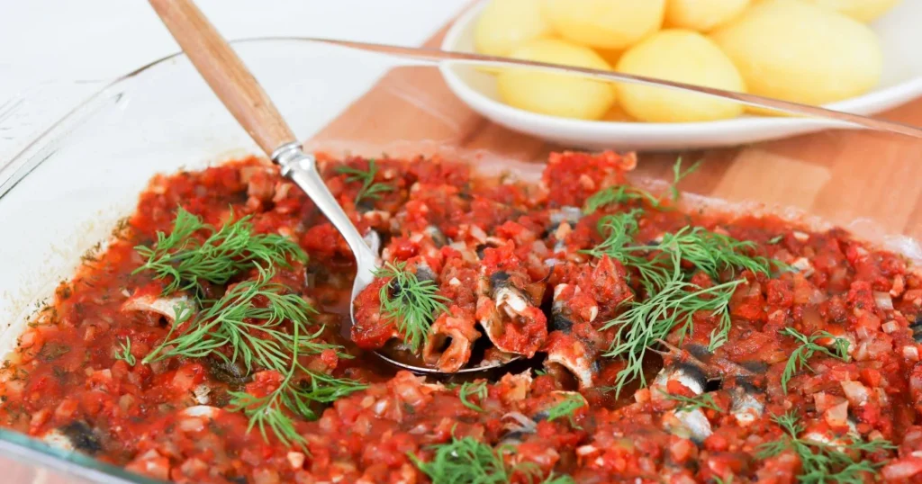 Tomaattisia silakkarullia uunivuoassa tillillä koristeltuna.