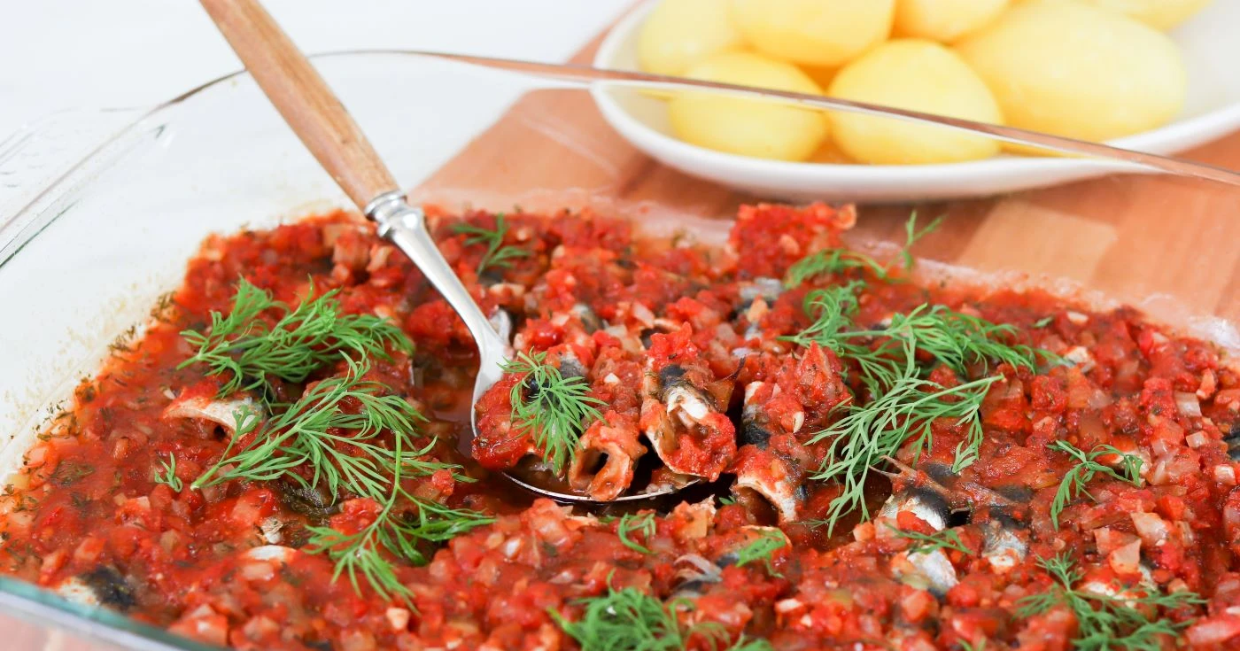 Tomaattisia silakkarullia uunivuoassa tillillä koristeltuna.