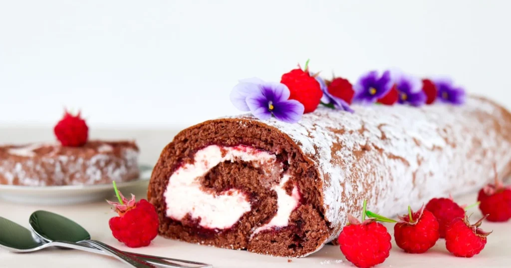 Vadelmakääretorttu tuoreiden vadelmien kera.