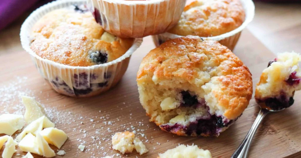 Valkosuklaa-mustikkamuffinsseja leikkuulaudalla.