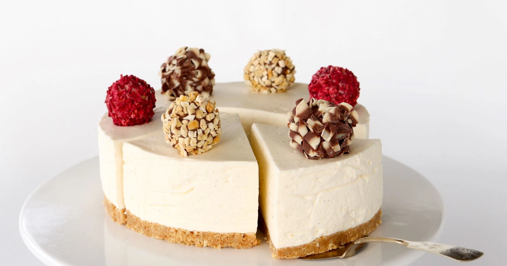 Vaniljajuustokakku isoilla ja pyöreillä suklaamakeisilla koristeltuna.