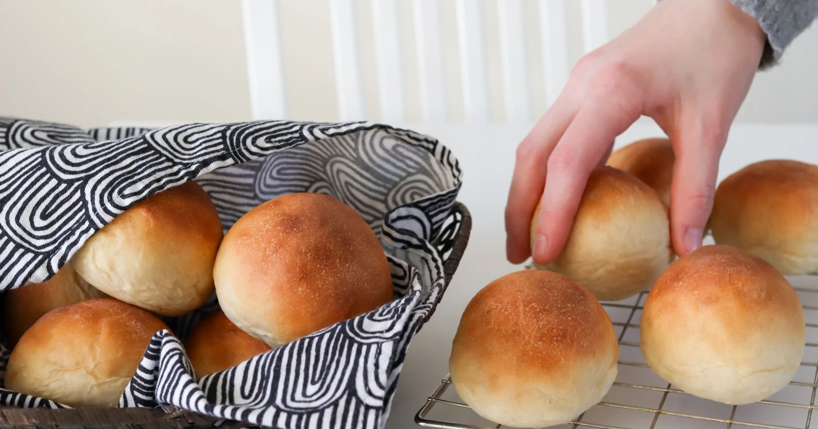 Tuoreet vehnäsämpylät korissa ja jäähdytysritilällä.