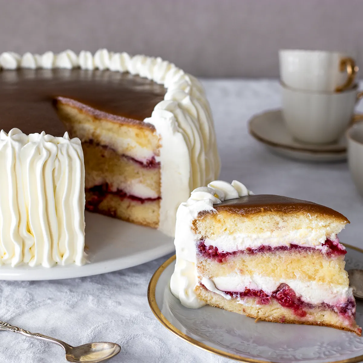 Täytetty vadelmakakku, josta on leikattu pala.