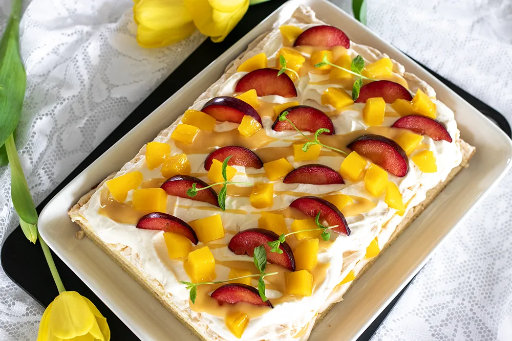 Hedelmäinen britakakku, jonka päällä on luumuja ja mangoa.