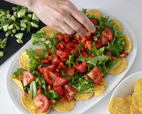 Tacosalaatin kokoaminen laakealle vadille.